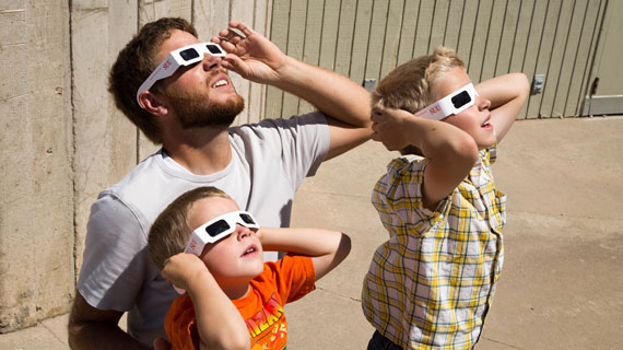 Children and parent looking at the sun with eclipse glasses
